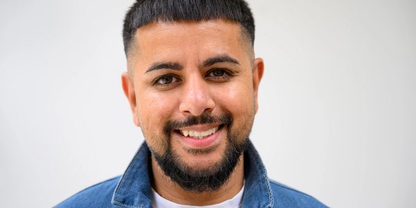 Smiling man with short hair and beard in denim jacket.