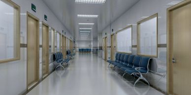 Empty hospital corridor with rows of chairs and closed doors.