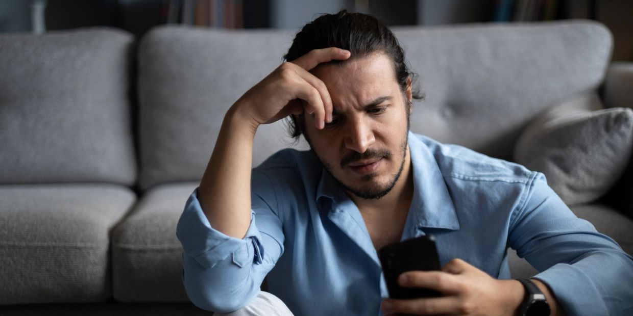 Man looks worried while checking his phone.