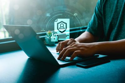 Person typing on a laptop with digital security icons.
