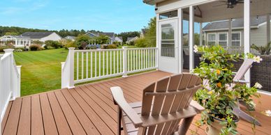 Sunny deck with chairs overlooking a green lawn.