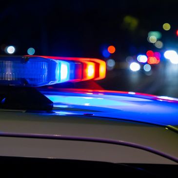 Close-up of flashing red and blue police lights on a car at night.
