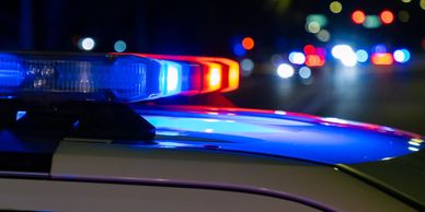 Close-up of flashing red and blue police lights on a car at night.