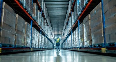 Person inspecting inventory in a large, organized warehouse.