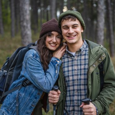 Young couple hiking in the forest, smiling and dressed warmly.