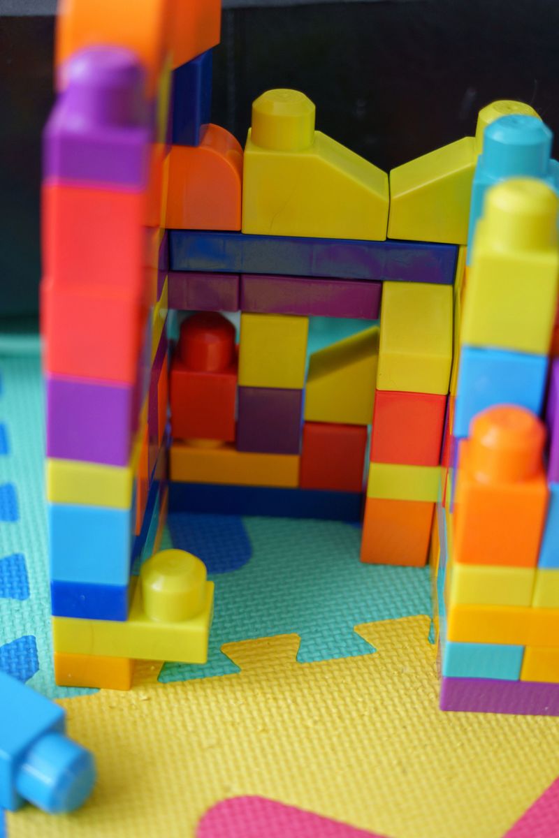colorful interlocking blocks forming a vibrant structure on a textured puzzle mat in a playful children's play area, surface, lively, cheerful, handmade, childhood, section, playroom, motley, floor