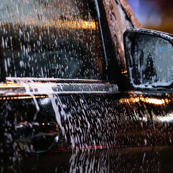 Close-up of soap suds covering a black car during a wash.