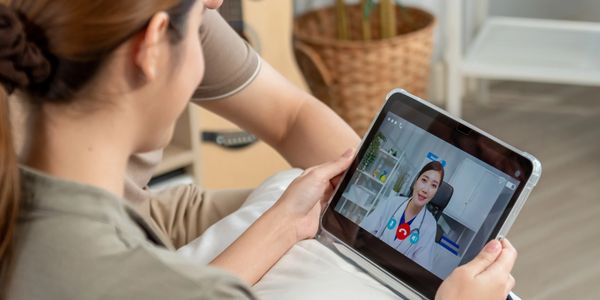 A woman video calling a female doctor on a tablet.