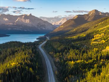 A serene landscape featuring a mountain, lake, and trees under a clear blue sky.