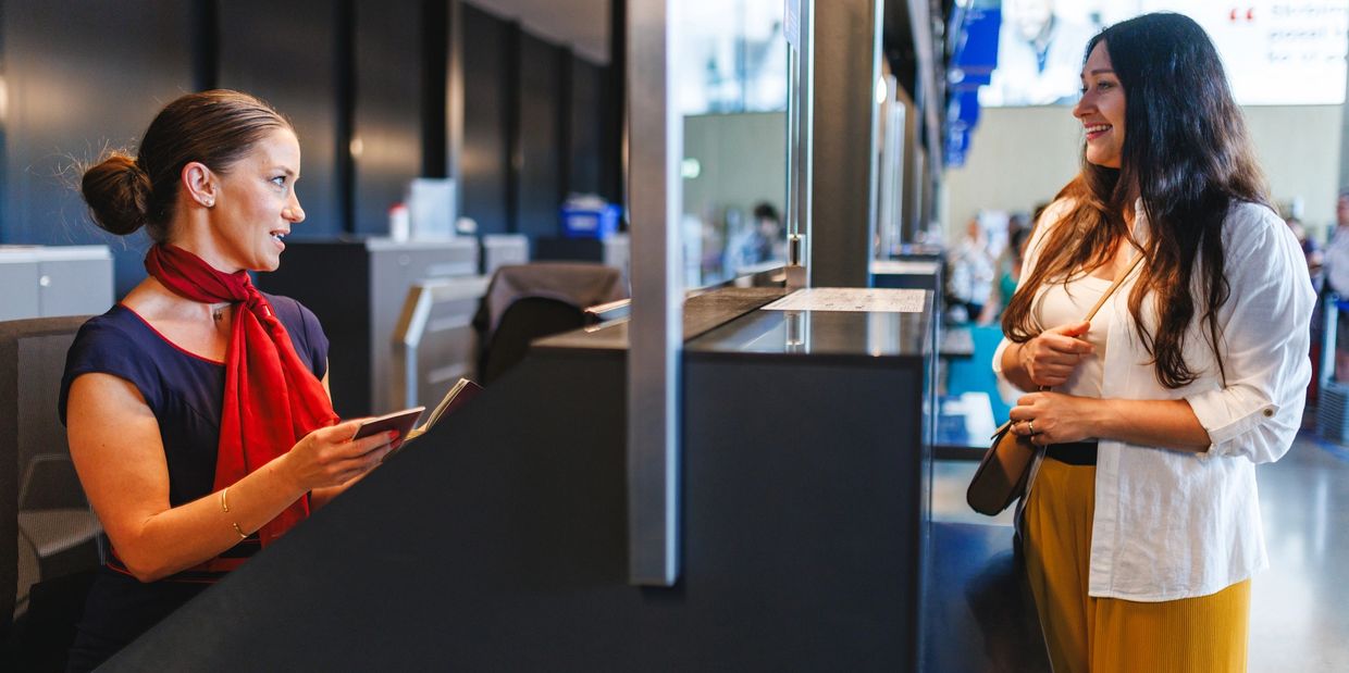 Woman at airport check-in counter holding passport.