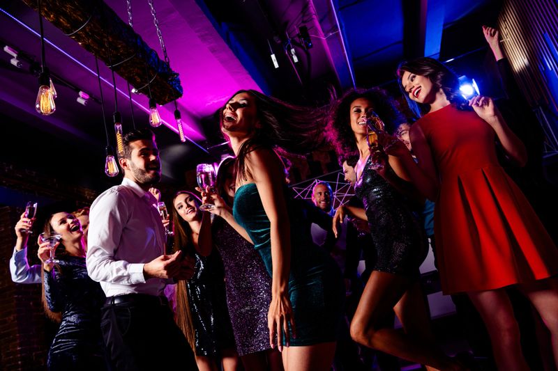 A lively party scene in a modern club with friends dancing and cheering under neon lights, capturing celebration fashion and vibrant nightlife energy among a joyful crowd.