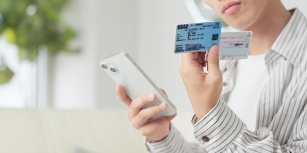 Person holding ID cards and smartphone.