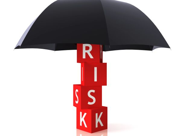 Black umbrella protecting red blocks spelling 'RISK'.