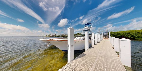 White boat docked at a marina on a sunny day with vibrant blue sky.