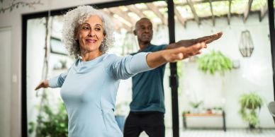 Older couple doing yoga together indoors.