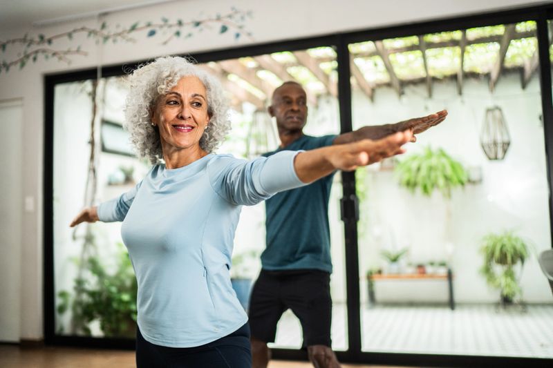 American senior woman doing yoga with husband at home