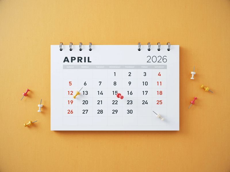 2026 April Calendar and Thumbtacks on Orange Background