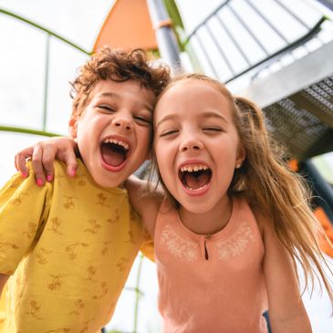 Two kids laughing joyfully at a playground.