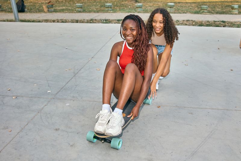 Two happy teenagers creatively enjoy skateboarding fun with smiles in an outdoor park setting.