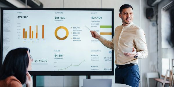 Man presenting financial data to colleague in office meeting.