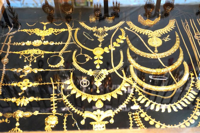 collection of gold jewelry, including necklaces, bracelets, and rings, displayed in a store.