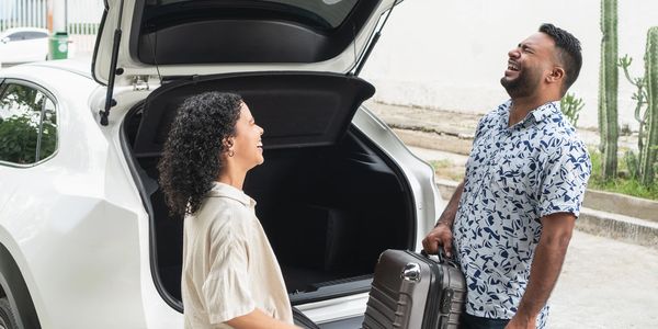 Happy customers laughing next to their rental car