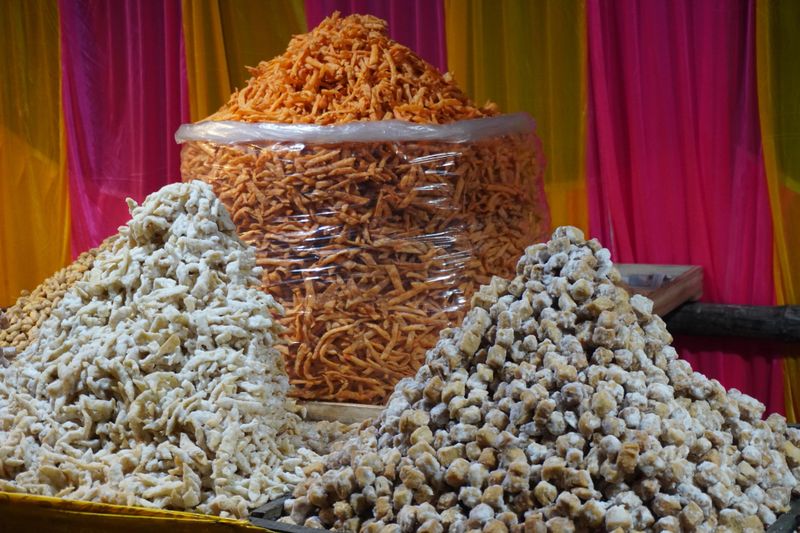 Colorful display of assorted Indian fried snacks piled high at festive street market stall