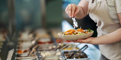 Person serving food at a buffet.