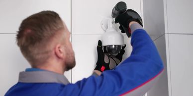 Technician installing a security camera on a wall.