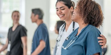 Two nurses sharing a warm moment in a hospital.