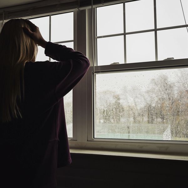 Person looking out rain-covered window, contemplative mood.