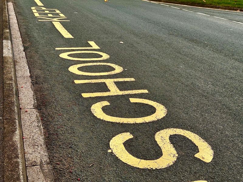 Yellow road markings advising drivers not to park outside a school