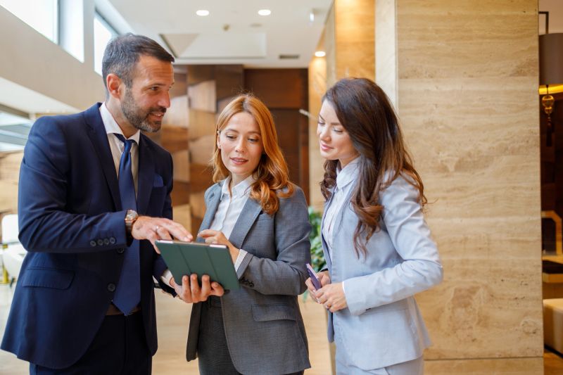 Three businesspeople discussing work, looking at content on a tablet. Focusing on teamwork and modern technology in business