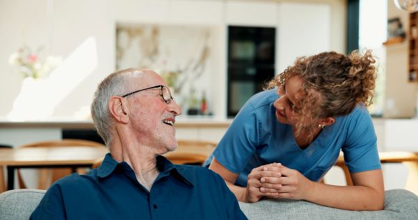 Young nurse talking to elderly man smiling.