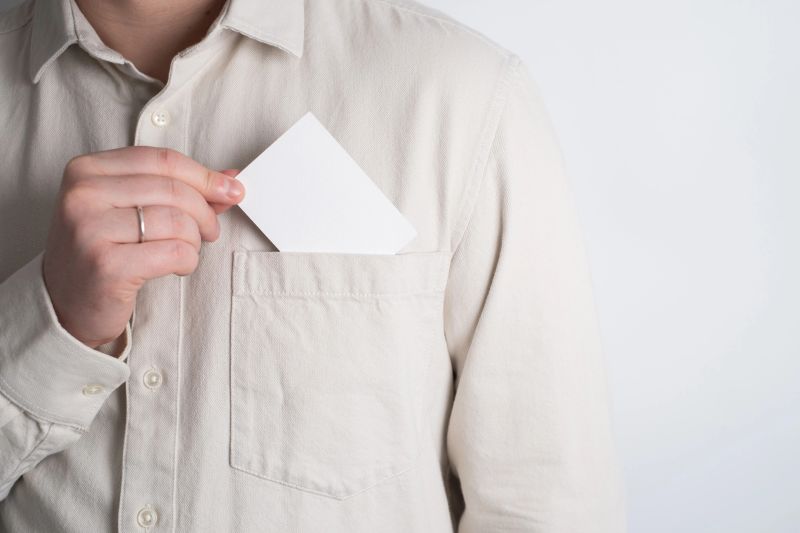 Hand taking a blank white card from a shirt pocket for personal branding. Business card mockup concept.