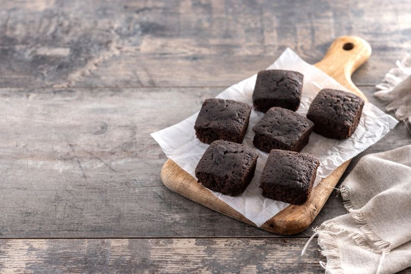 Homemade chocolate brownies with sugar powder on wooden table.