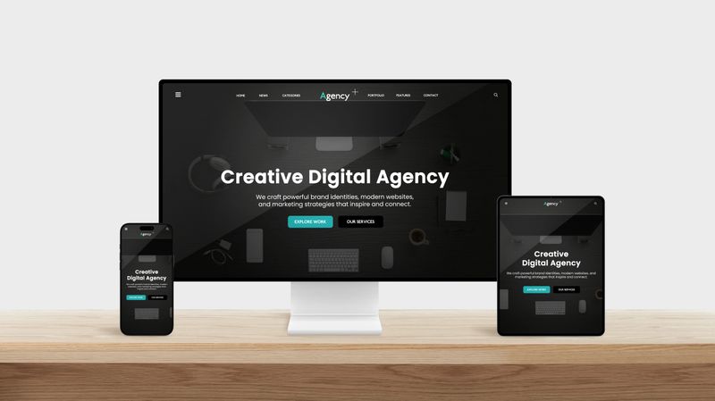 Modern workspace with desktop, tablet, and smartphone showing responsive web design interface of a creative digital agency on sleek wooden desk with minimalist background