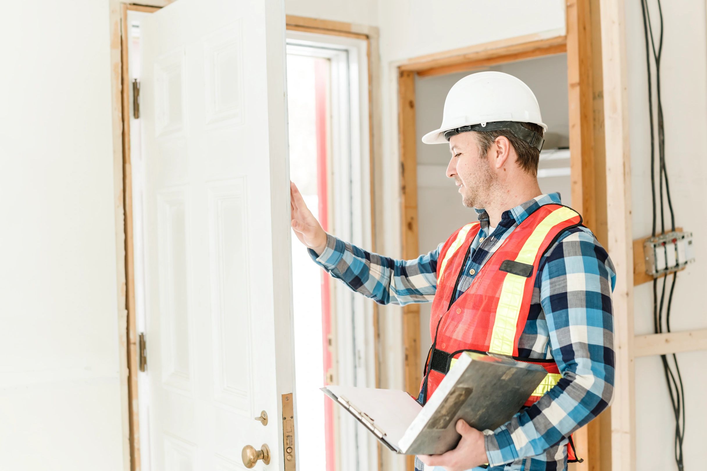 Construction worker inspecting a white door on site.