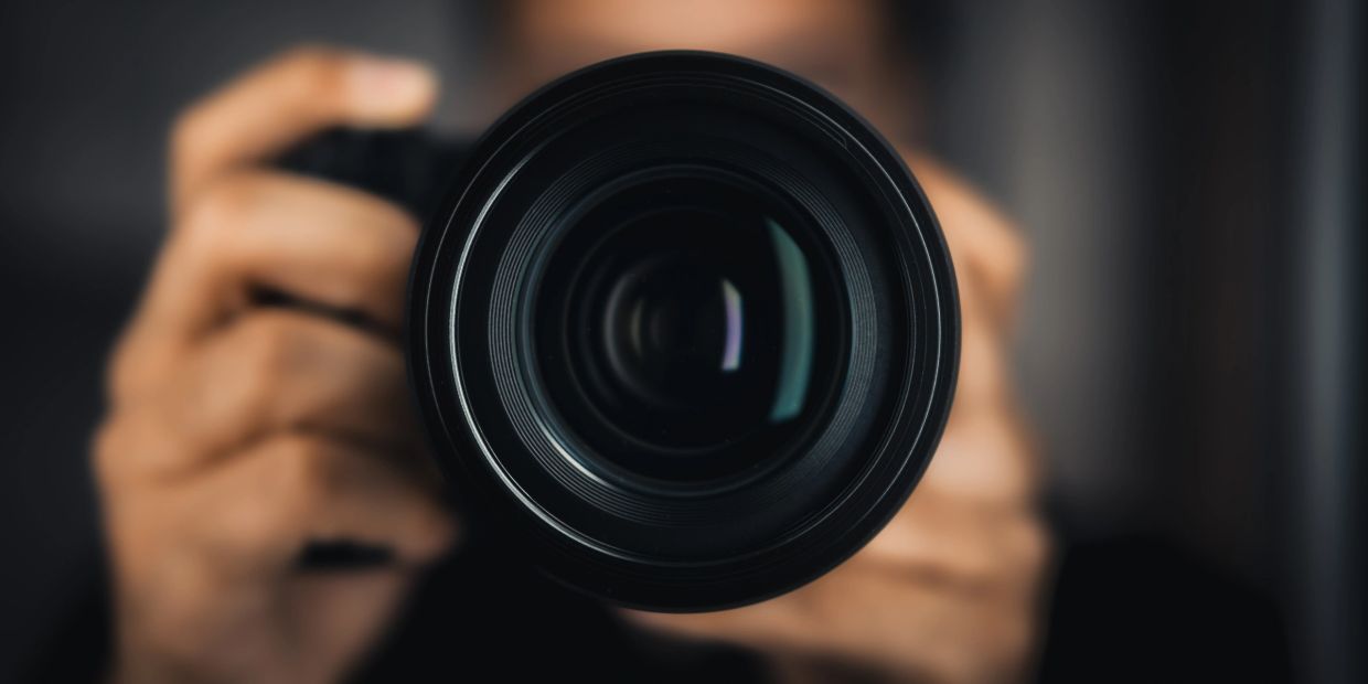 Close-up of a camera lens held by a person.