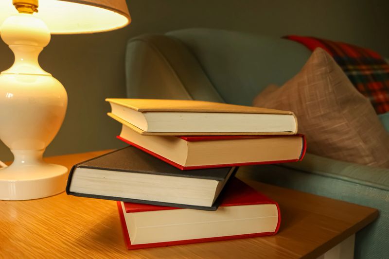 Stacked books illuminating under a gentle lamp light, creating a relaxing ambiance for reading, education, and study in a home