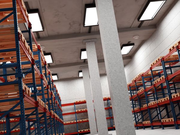 Empty industrial warehouse with tall metal shelving units and concrete pillars.