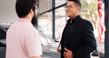 Silver Jeep SUV with American flags and dealership tag.
