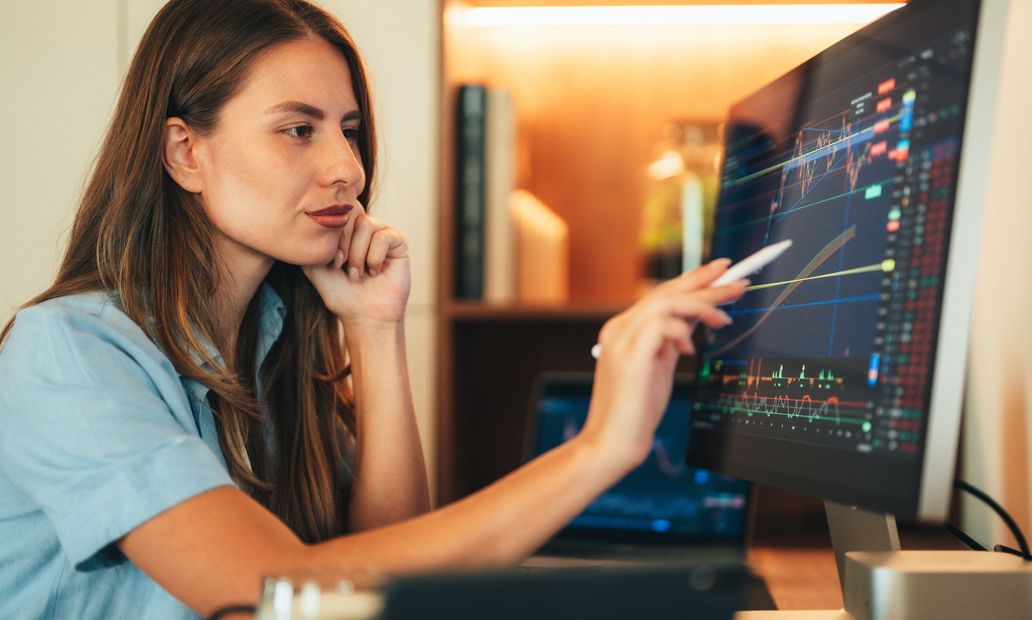 Woman analyzing stock charts on computer screen.