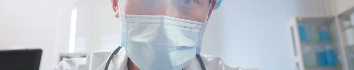 Doctor wearing mask and stethoscope in medical setting.