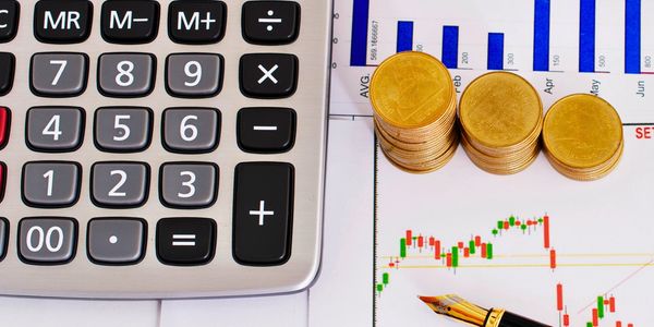 Calculator, stacked coins, and financial charts with a pen.
