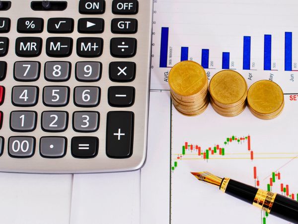Calculator, coins, and financial charts with a pen for analysis.