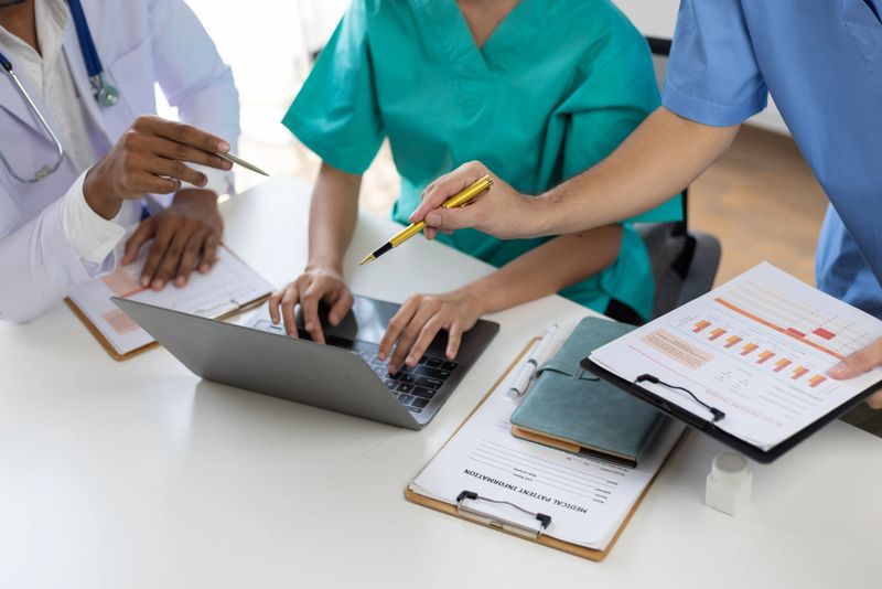Medical team discussing patient data on laptop during meeting, discussing patient data and treatment plans, teamwork and innovation in healthcare.