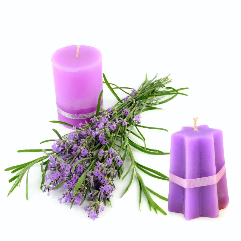 Two purple pillar and star-shaped candles are arranged with a fresh bouquet of fragrant lavender flowers, captured against a clean white background. This image perfectly evokes a feeling of calm and relaxation, ideal for beauty, spa, or wellness themes.
