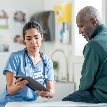 A nurse showing a patient information on a tablet in a clinic.