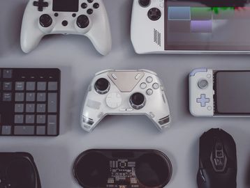 Various gaming devices and controllers arranged on a gray surface.